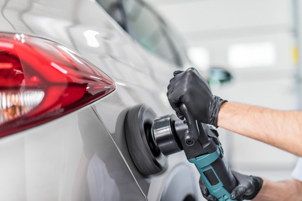 Car detailing - Man holds a polisher in the hand and polishes the car. Selective focus.