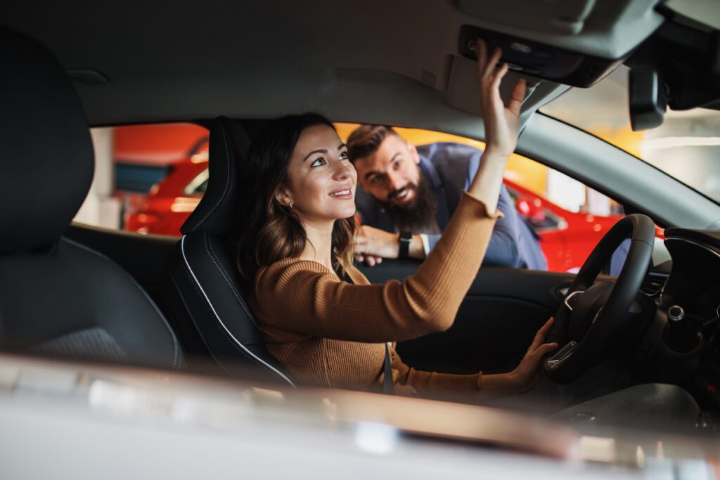 Happy young couple is  buying a new car at the car showroom.