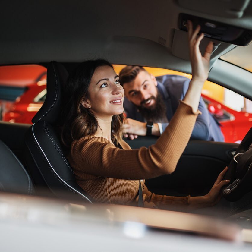 Happy young couple is  buying a new car at the car showroom.